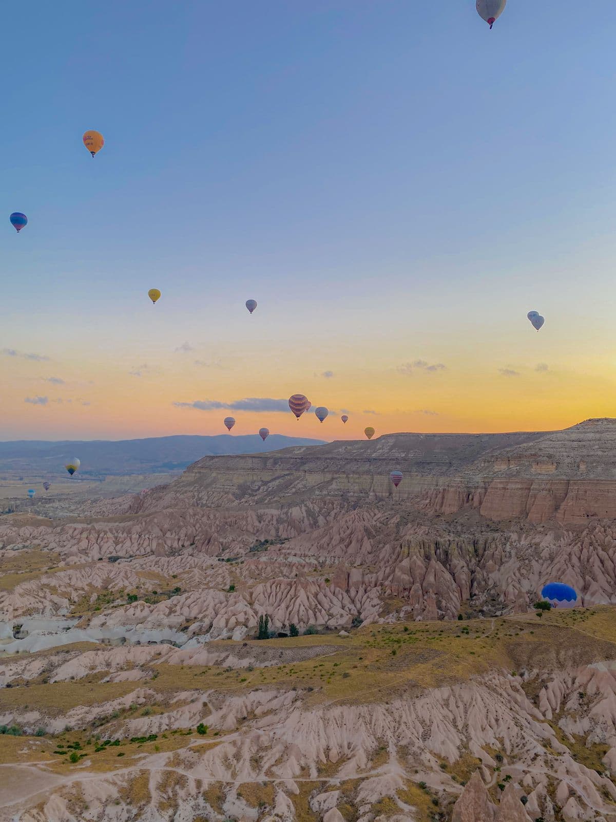 Der Korb eines Heißluftballons schwebt bei Sonnenaufgang über den Tälern Kappadokiens
