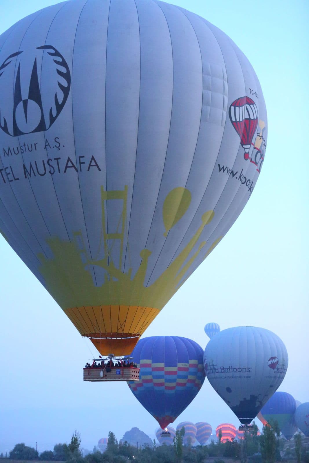 Pasajeros asomados al borde de la cesta de un globo aerostático sobre Capadocia