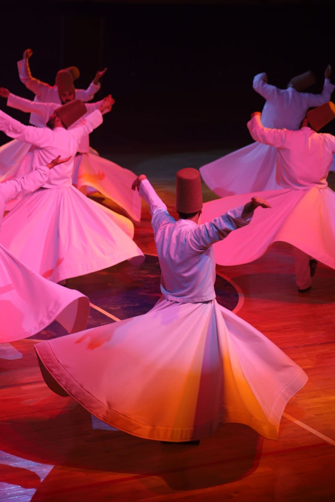Whirling dervishes performing under stage lights at a Turkish night show